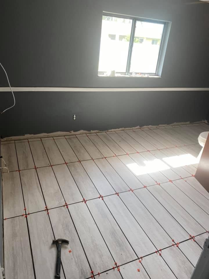 Wood-look plank tile floor being laid with leveling spacers in a freshly painted room