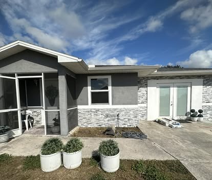 Home exterior with stone veneer, fresh gray paint, and a screened front porch