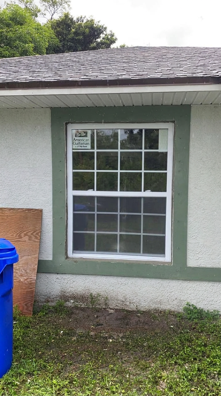 New white grid window installed in a green-trimmed exterior wall